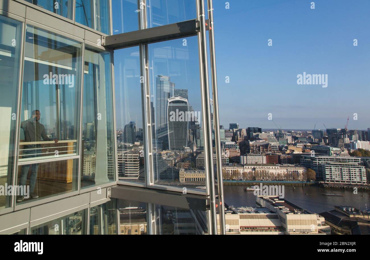 Geschäftsmann spricht mit Smartphone am sonnigen, modernen Hochhausfenster Stockfoto