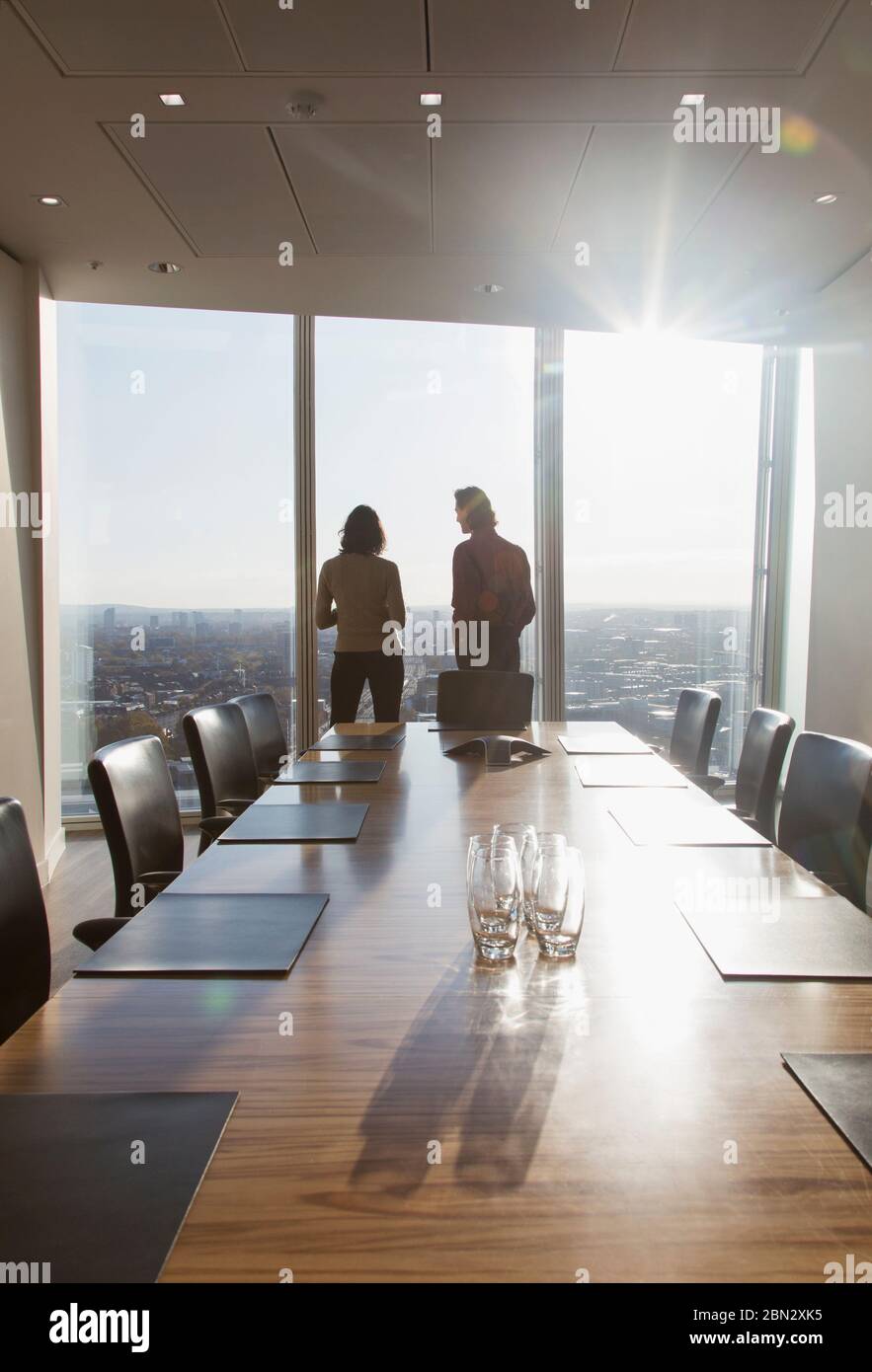 Geschäftsleute stehen am sonnigen Fenster des Konferenzraums Stockfoto