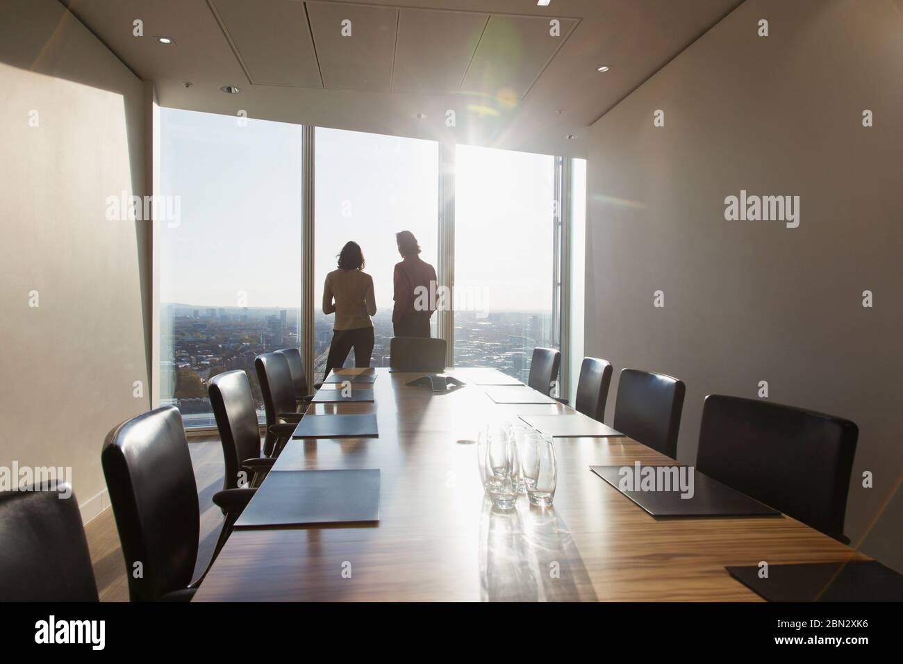 Geschäftsleute sprechen im sonnigen Hochhaus mit dem Fenster des Konferenzraums Stockfoto