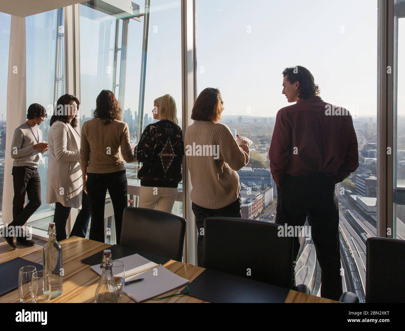 Geschäftsleute, die sich am Fenster des städtischen Konferenzraums unterhalten Stockfoto