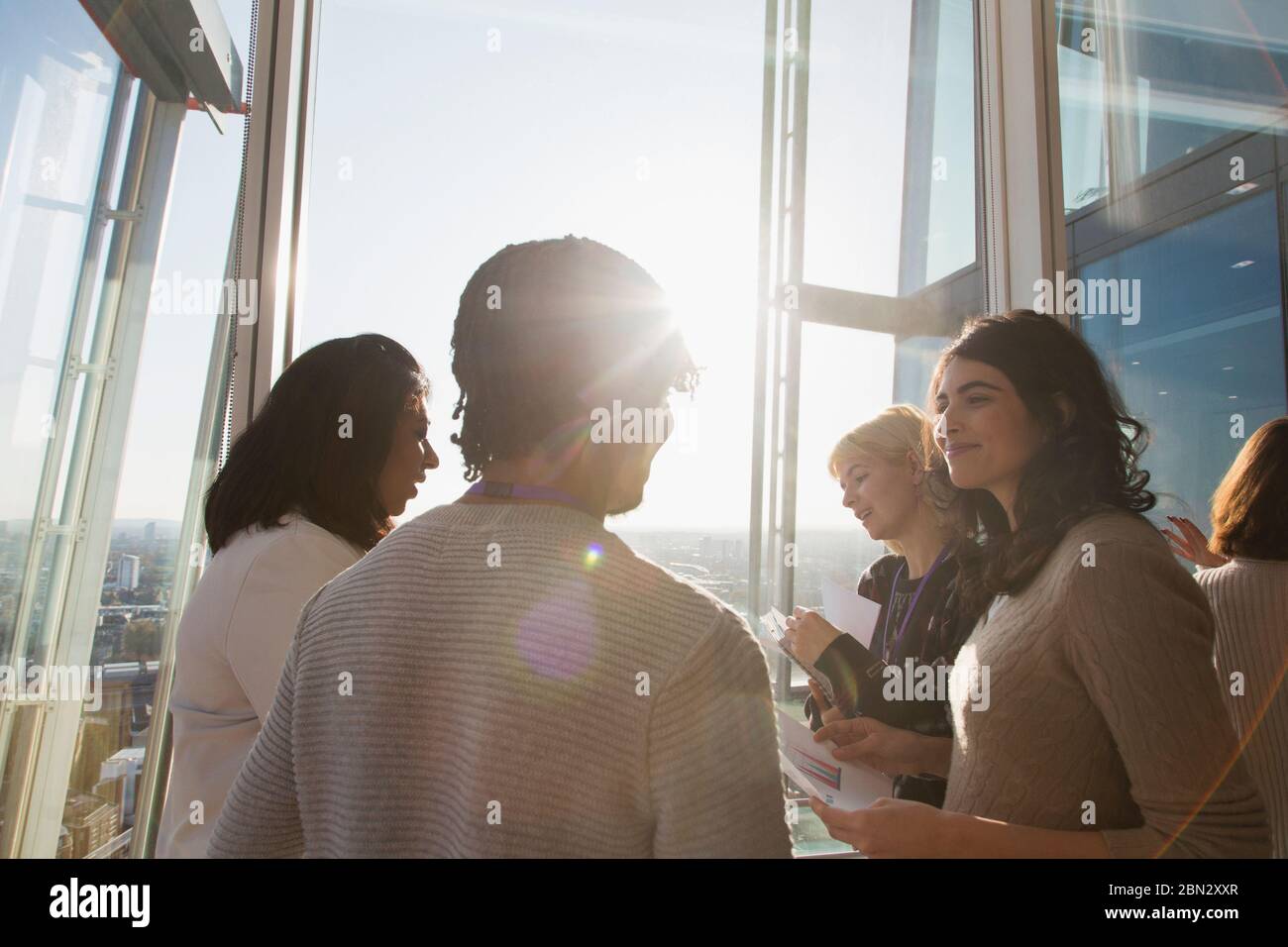 Geschäftsleute sprechen im sonnigen Bürofenster Stockfoto