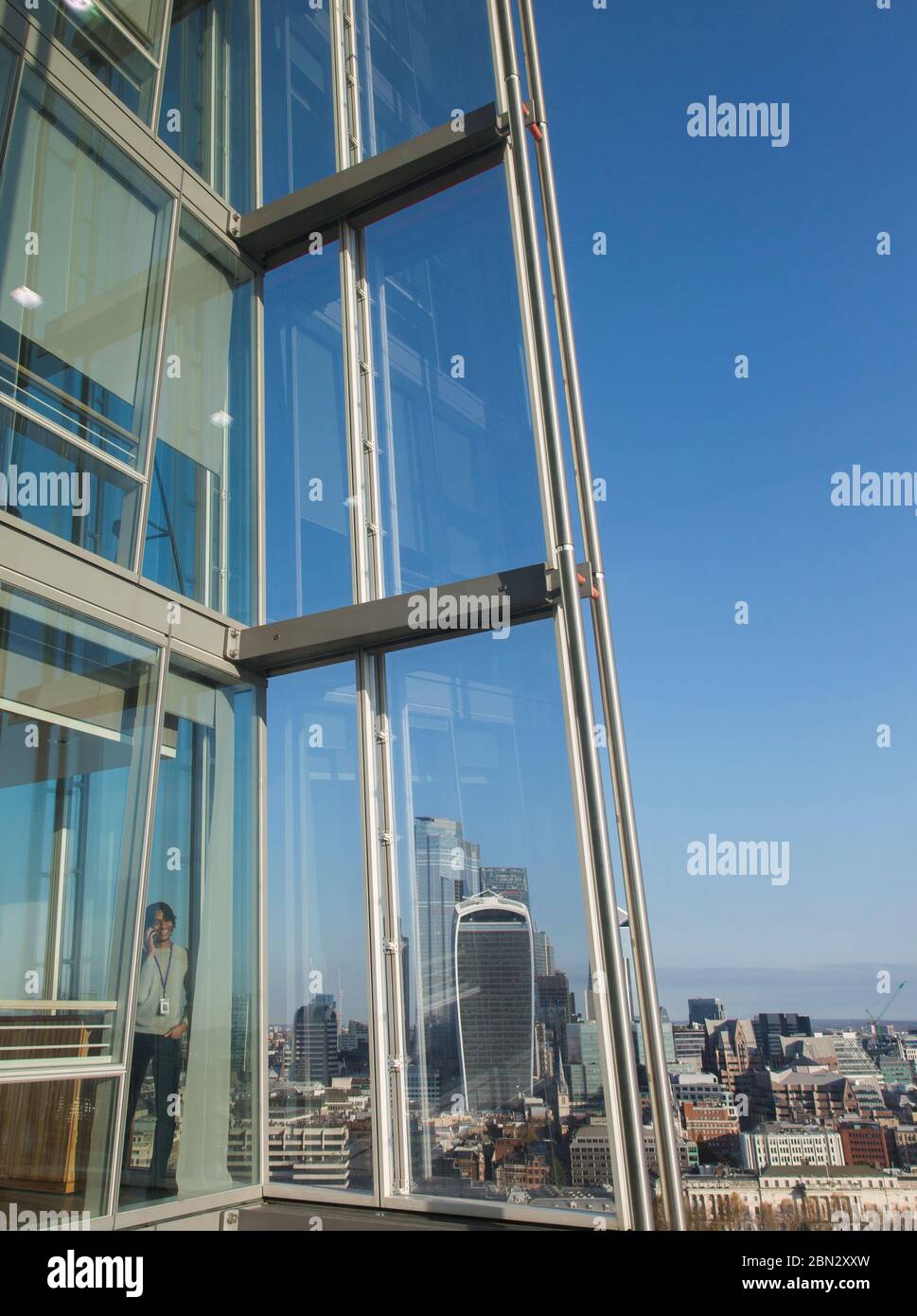Geschäftsmann mit Smartphone am sonnigen städtischen Hochhaus Bürofenster Stockfoto