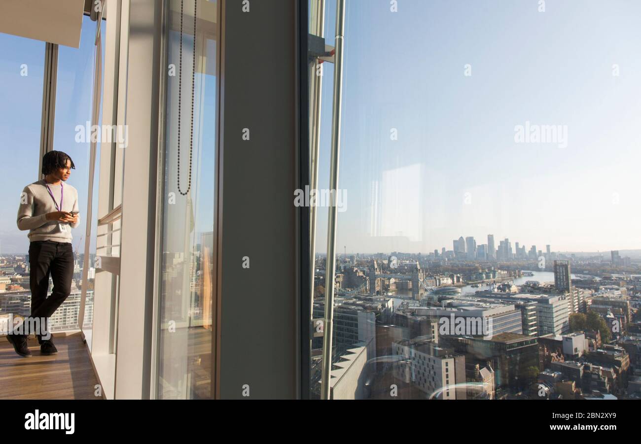 Geschäftsmann steht am sonnigen städtischen Hochhaus Bürofenster Stockfoto