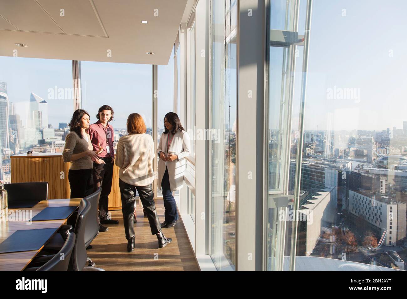 Geschäftsleute sprechen am sonnigen Hochhaus Bürofenster Stockfoto