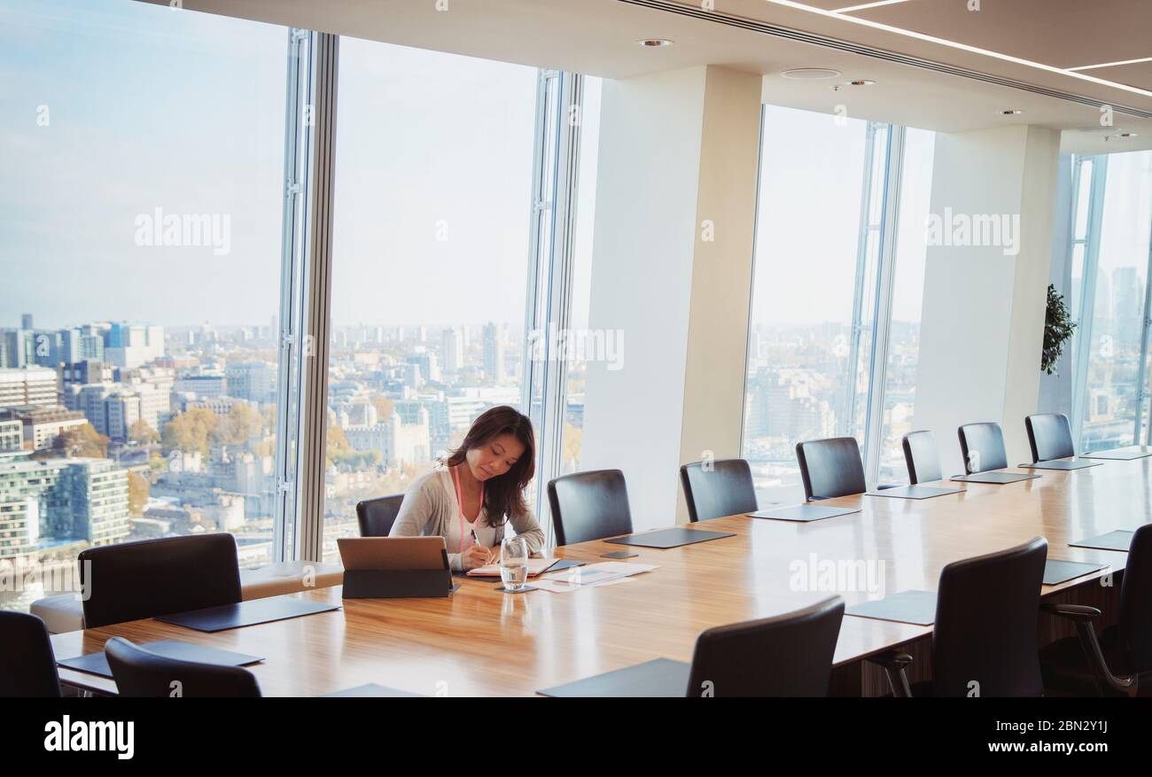 Engagierte Geschäftsfrau bereitet sich in sonnigen städtischen Konferenzraum Stockfoto