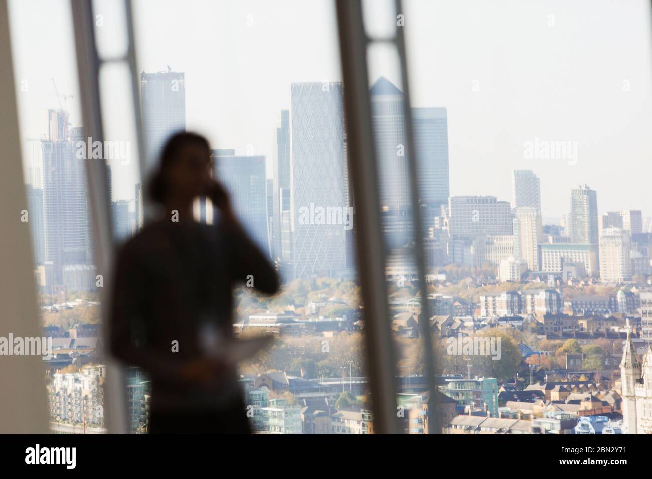 Geschäftsmann spricht auf Smartphone in sonnigen städtischen Bürofenster Stockfoto