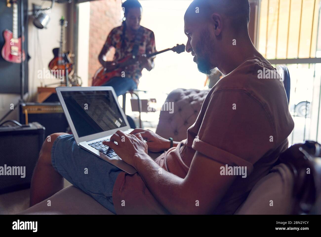 Musiker mit Laptop und Gitarre im Tonstudio Stockfoto