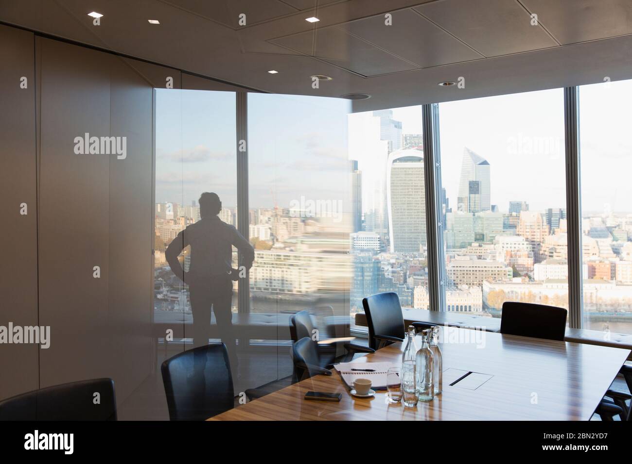 Silhouette Geschäftsmann stehend am städtischen Hochhaus Büro Fenster Stockfoto