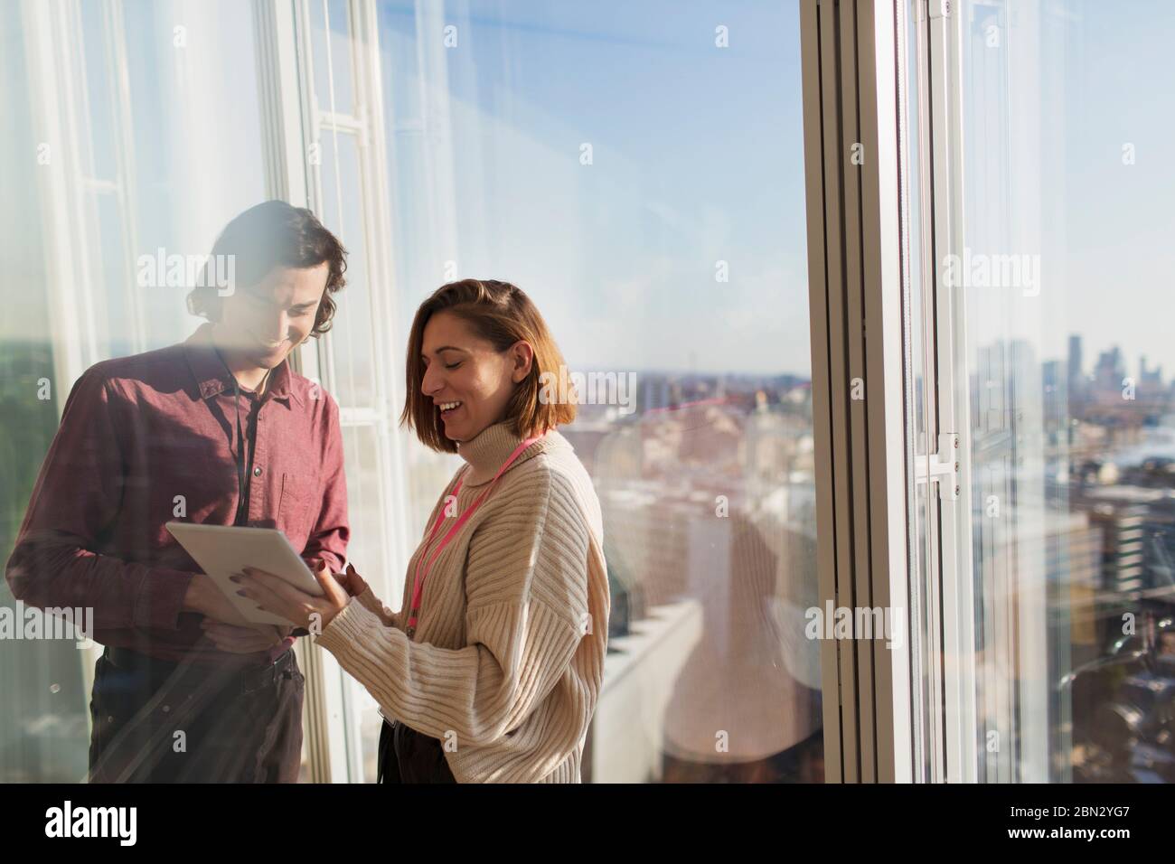 Geschäftsleute, die ein digitales Tablet am sonnigen Bürofenster im Stadtbereich verwenden Stockfoto