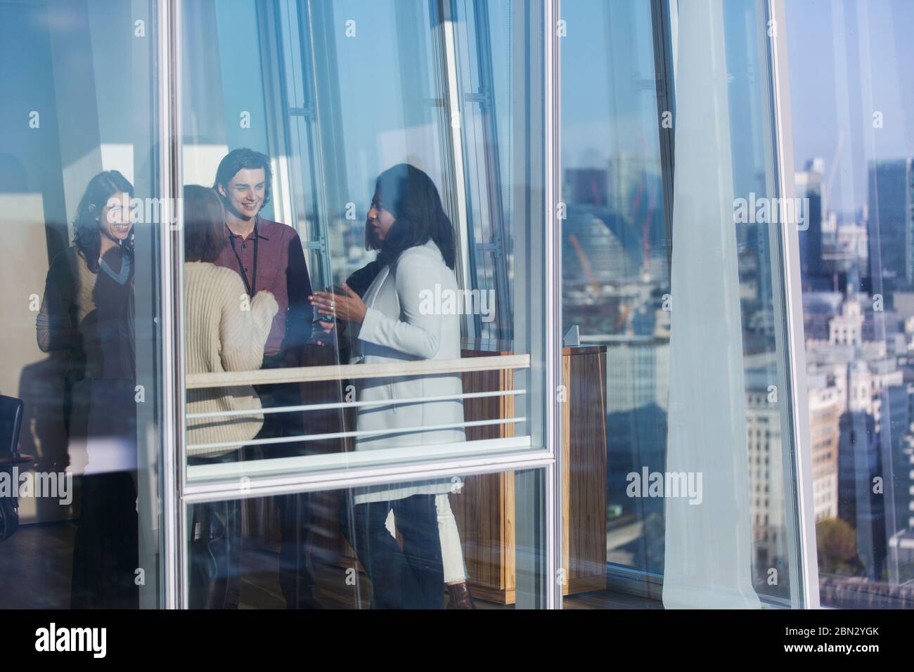 Geschäftsleute sprechen im sonnigen städtischen Bürofenster Stockfoto