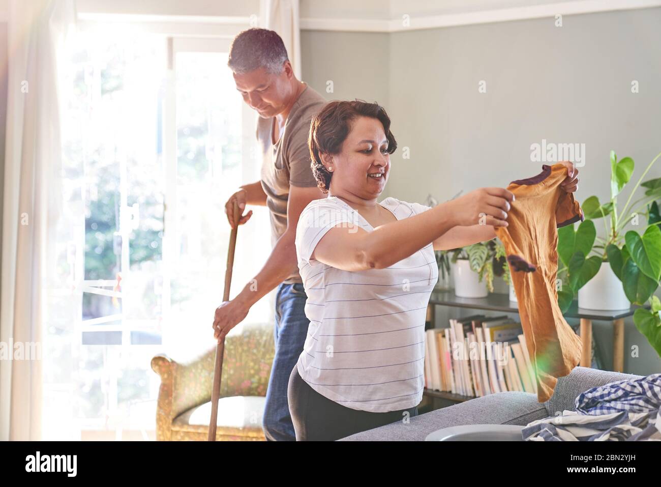 Ältere paar Falten Kleidung und fegen zu Hause Stockfoto