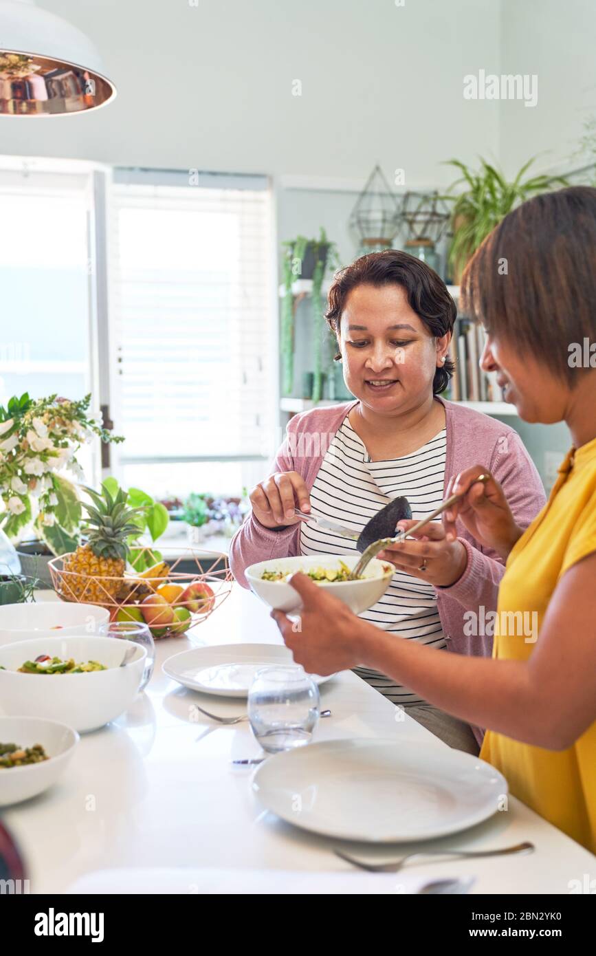 Freundinnen essen Salat auf der Kücheninsel Stockfoto