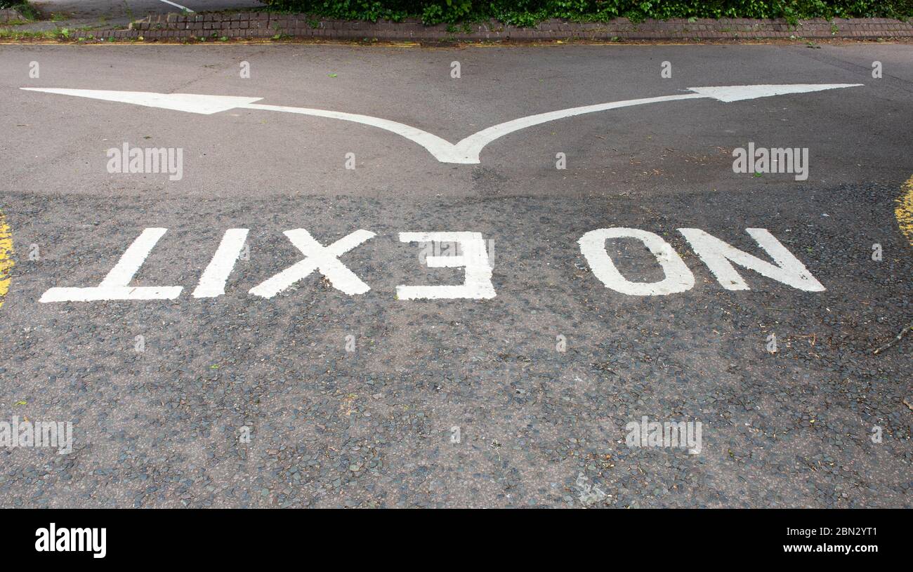 No Exit weiß auf die Straße gestrichen und auf den Kopf gestellt mit einem geteilten Pfeil, der alternative Richtungen anzeigt Stockfoto