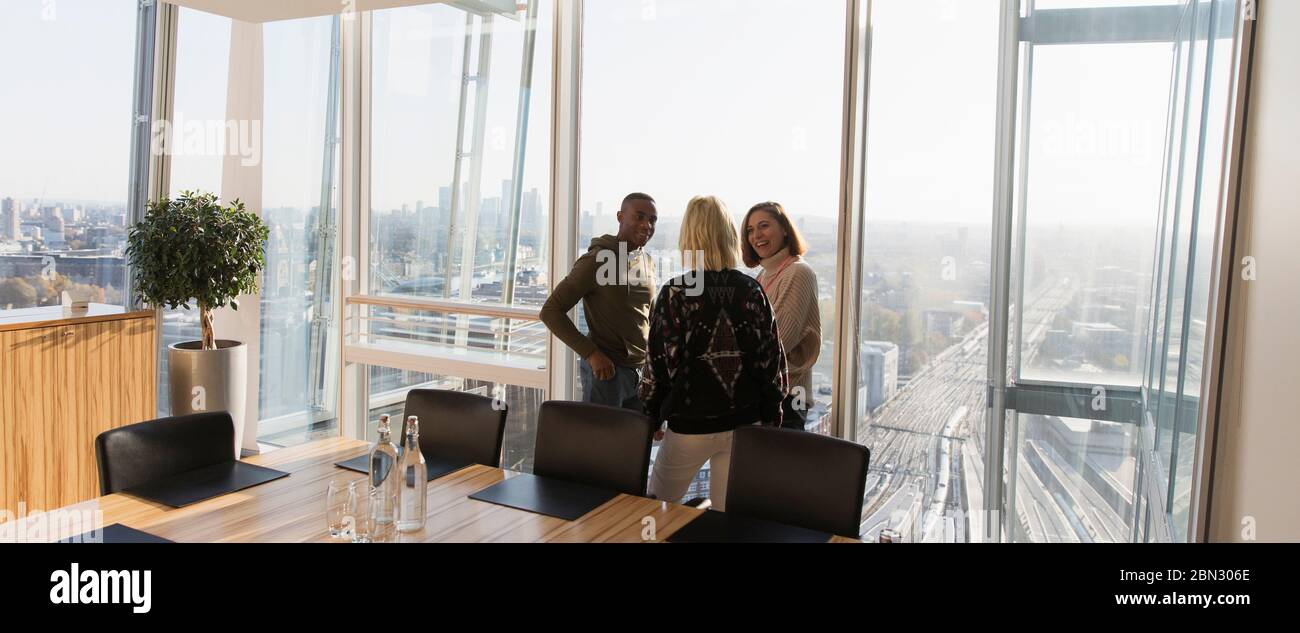 Geschäftsleute sprechen am sonnigen Hochhaus Bürofenster Stockfoto