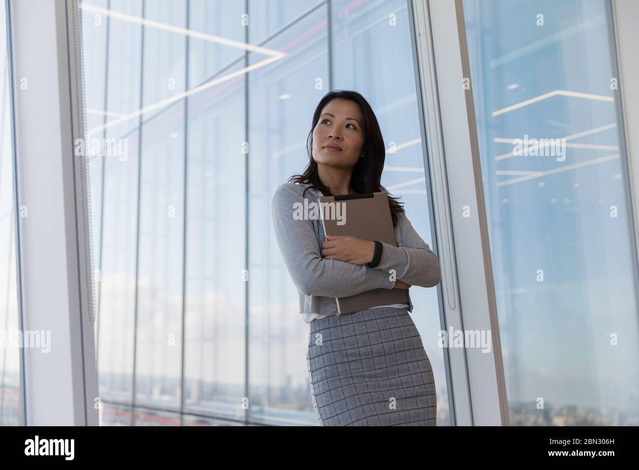 Durchdachte Geschäftsfrau hält digitale Tablette am Hochhaus Fenster Stockfoto