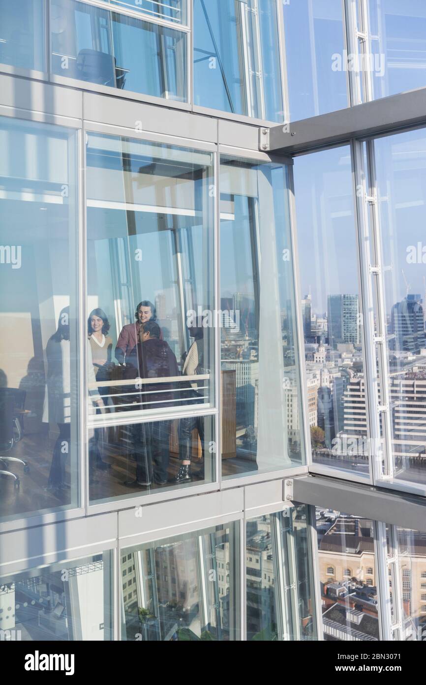 Geschäftsleute sprechen im sonnigen, modernen Hochhaus-Bürofenster Stockfoto