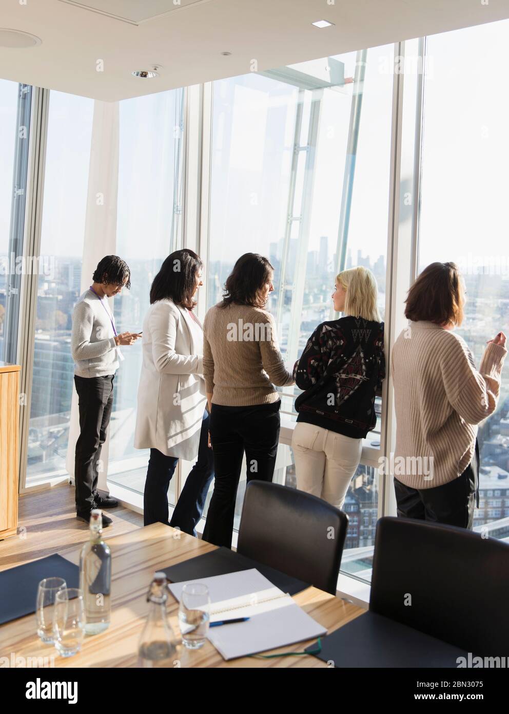 Geschäftsleute sprechen am sonnigen Fenster des Konferenzraums Stockfoto