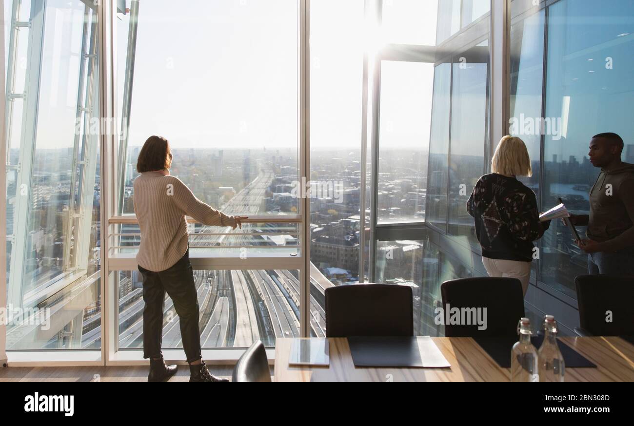 Geschäftsfrauen stehen am sonnigen städtischen Hochhaus Bürofenster Stockfoto
