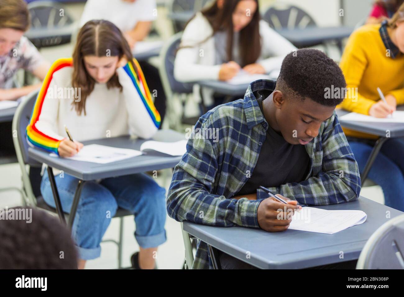 Fokussierte High School Jungen Schüler, die Prüfung am Schreibtisch im Klassenzimmer Stockfoto