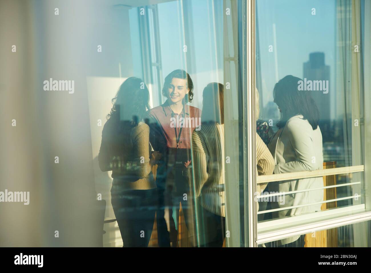 Geschäftsleute, die sich im sonnigen Bürofenster unterhalten Stockfoto