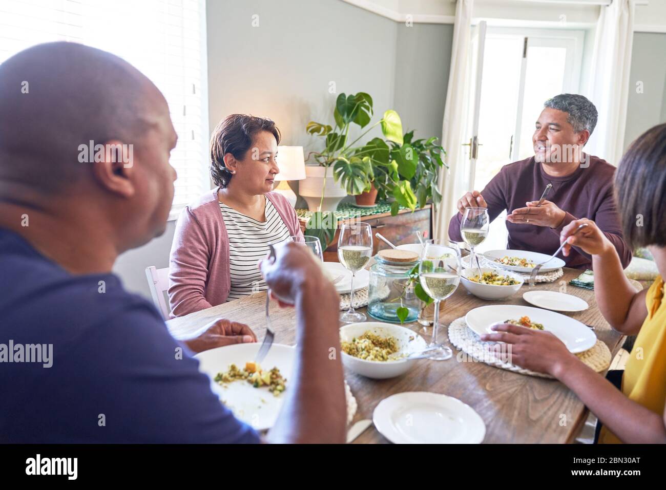 Ältere Freunde sprechen und essen am Esstisch Stockfoto