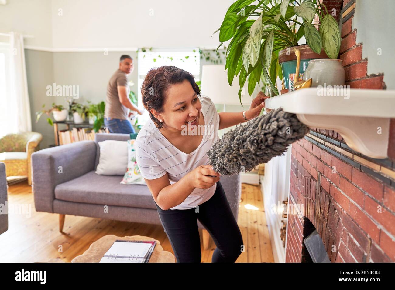 Reife Frau mit Staubstaub Kamin Mantel Stockfoto