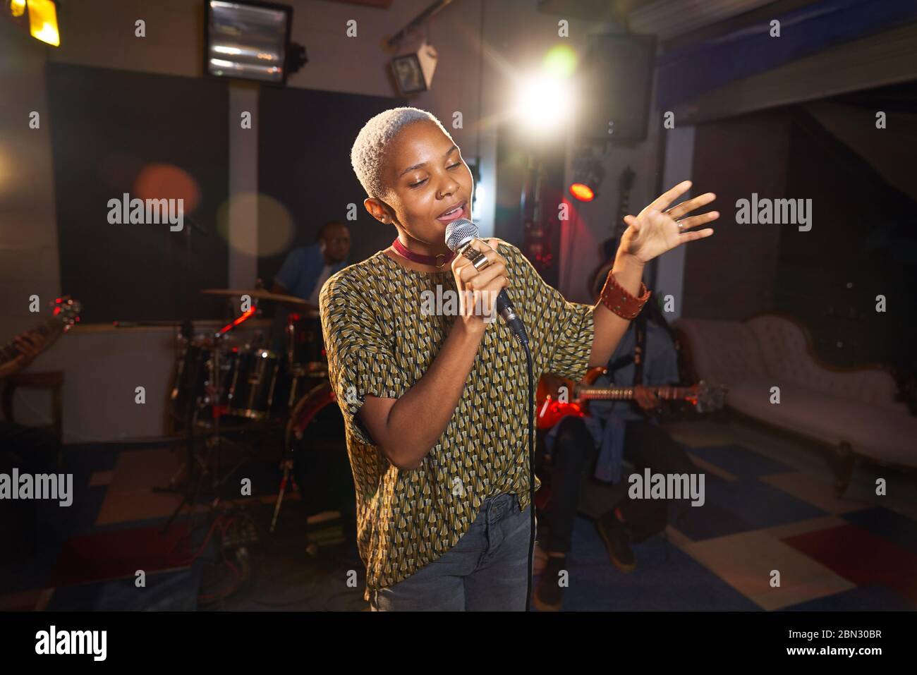 Junge Musikerin singt ins Mikrofon im Aufnahmestudio Stockfoto