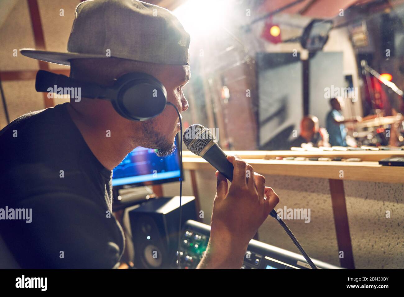 Männlicher Produzent mit Mikrofon, der im Musikaufnahmestudio arbeitet Stockfoto