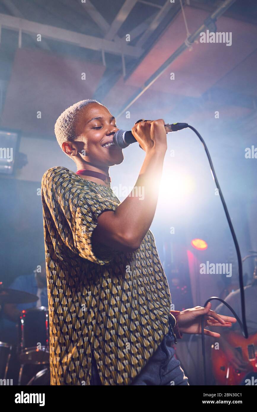 Junge Musikerin singt ins Mikrofon im Aufnahmestudio Stockfoto