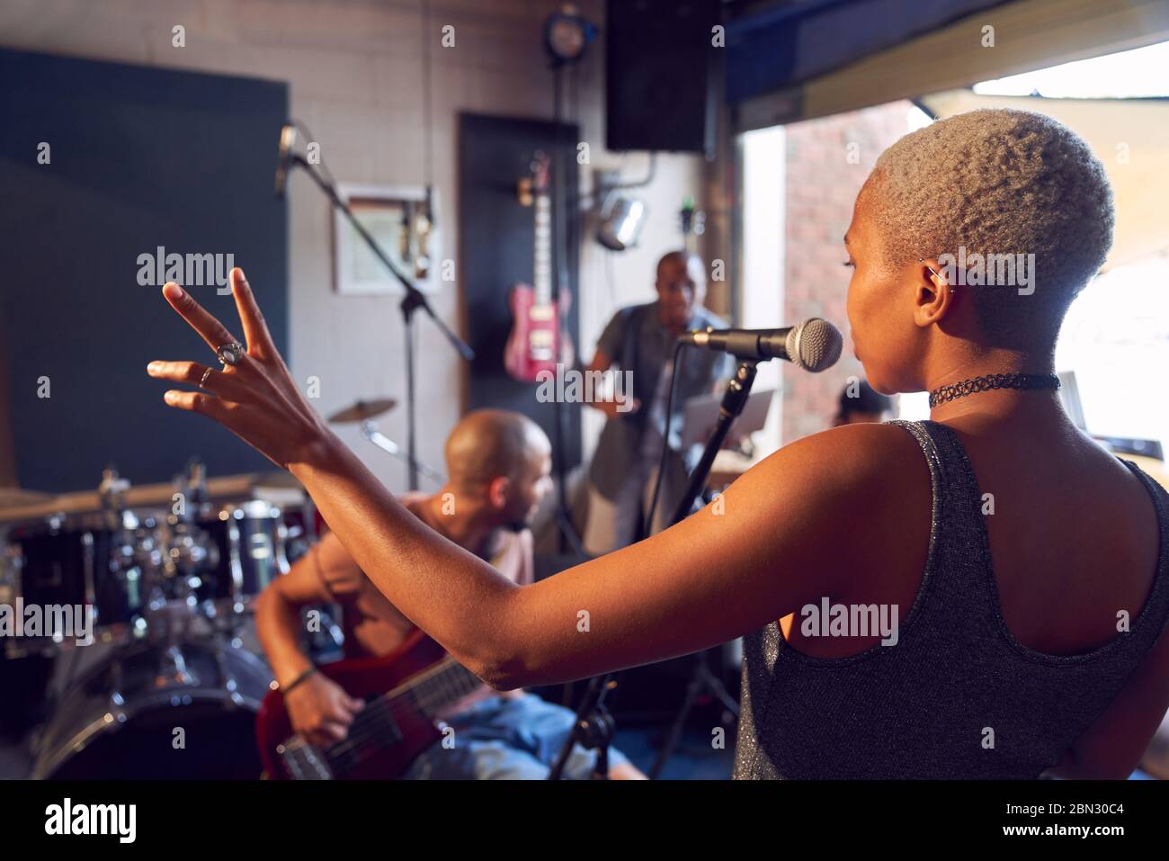 Musikerin singt ins Mikrofon im Garagenaufnahmetudio Stockfoto