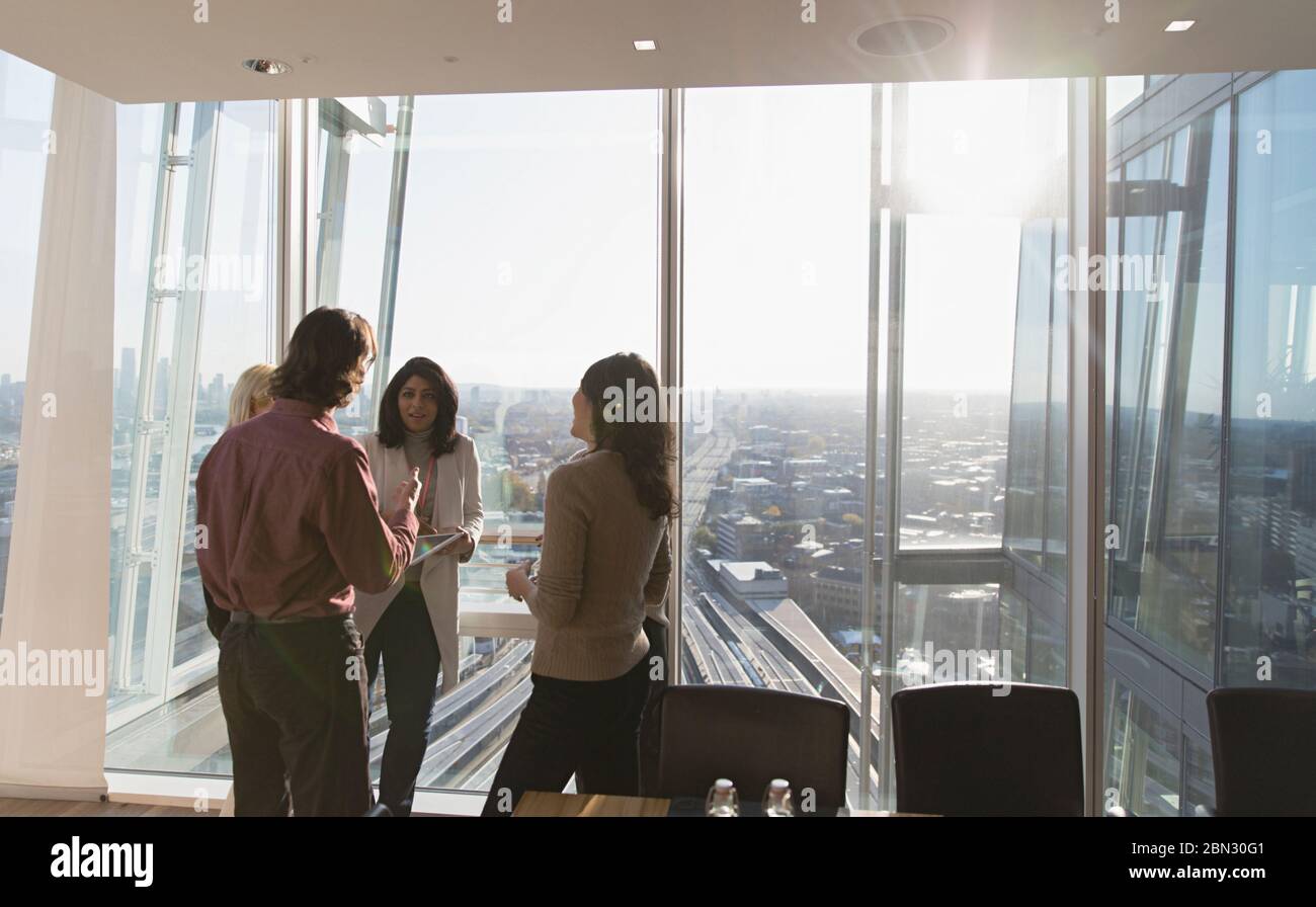Geschäftsleute sprechen am sonnigen Hochhaus Bürofenster Stockfoto