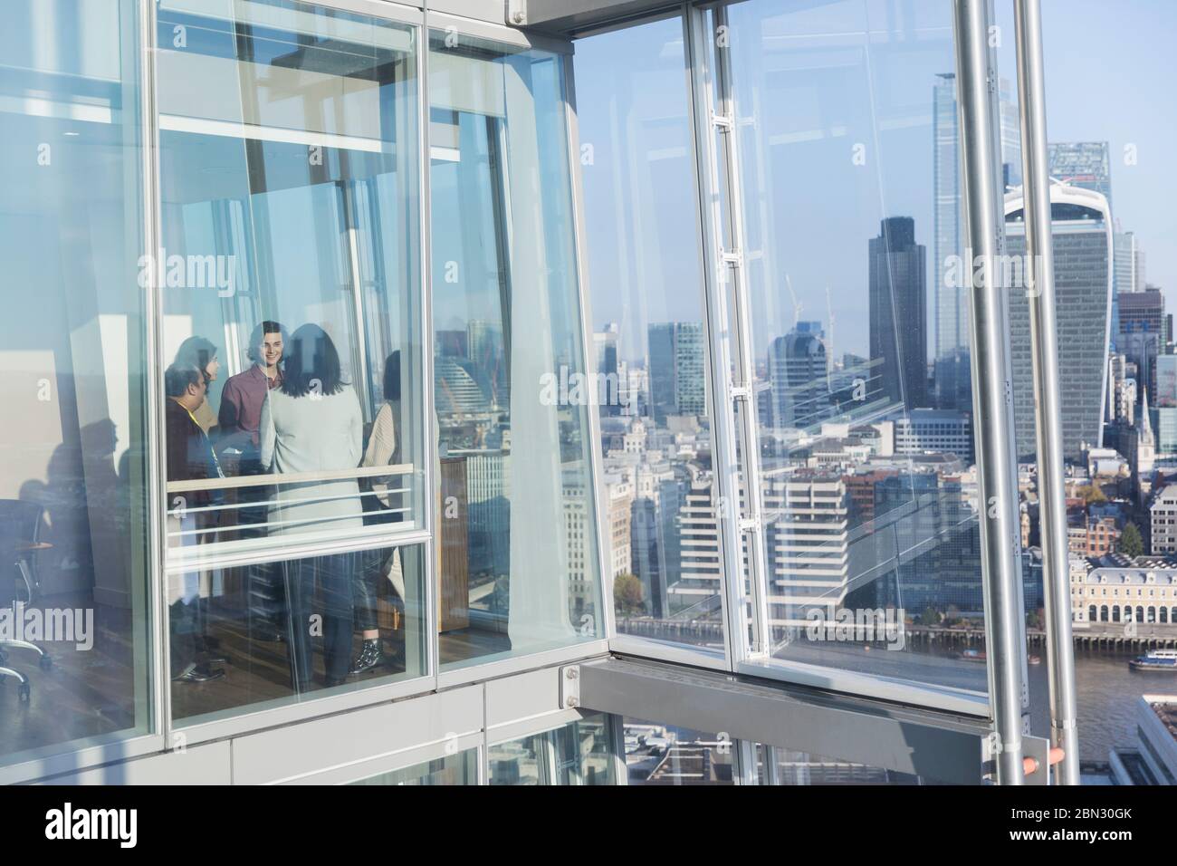 Geschäftsleute sprechen am sonnigen städtischen Hochhaus Bürofenster Stockfoto