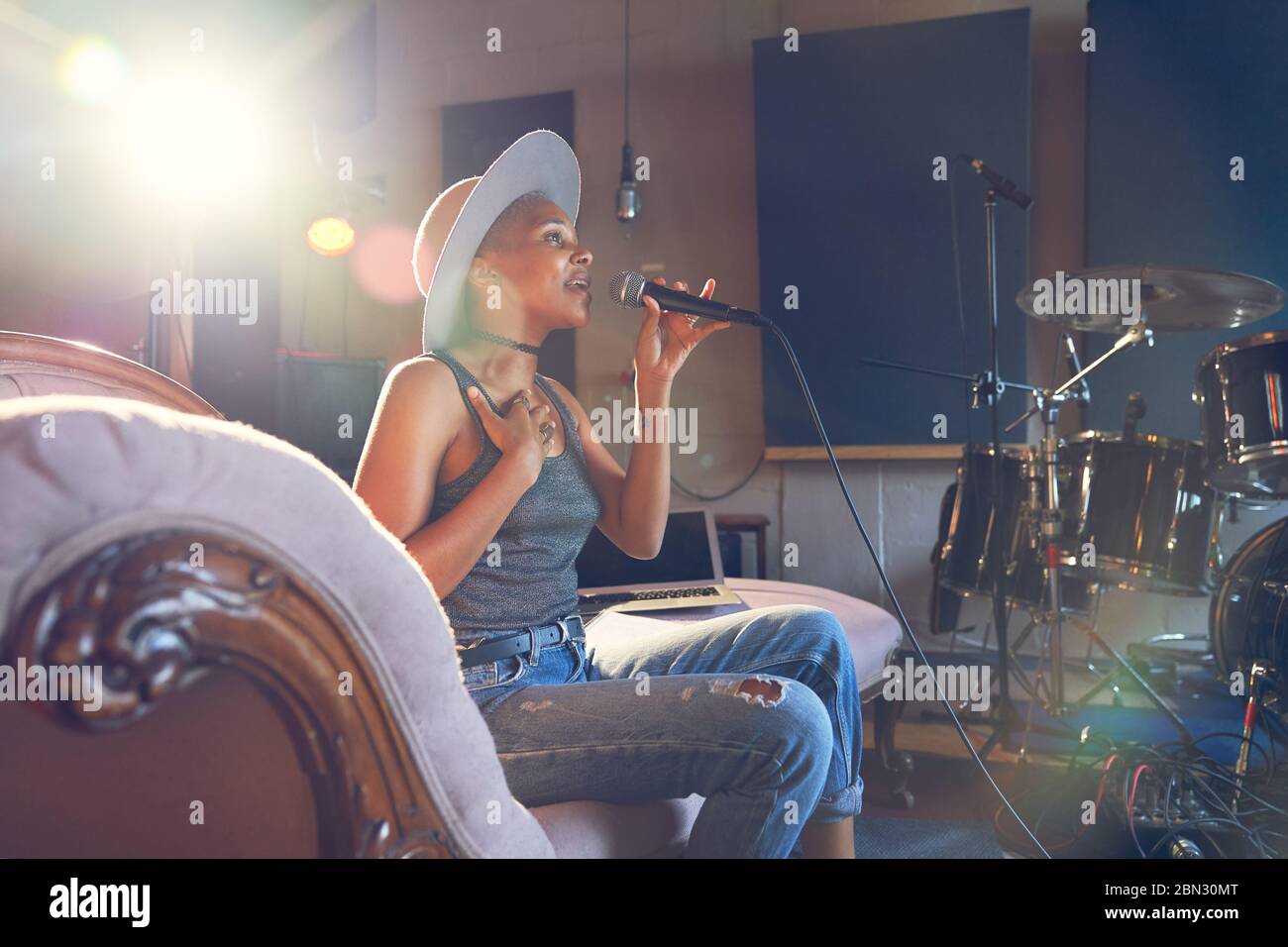 Junge Musikerin singt ins Mikrofon im Aufnahmestudio Stockfoto