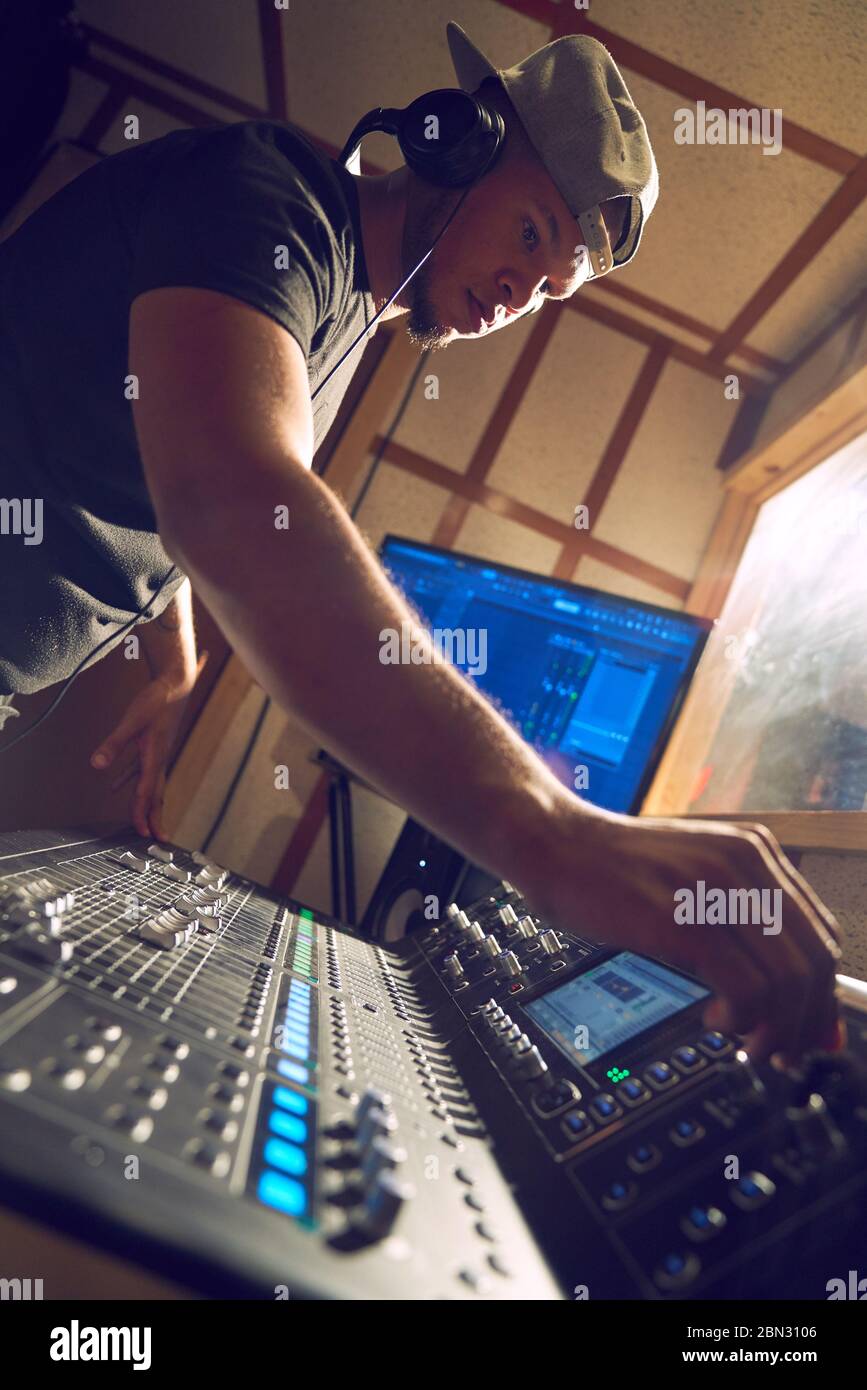 Männlicher Musikproduzent am Soundboard im Tonstudio Stockfoto
