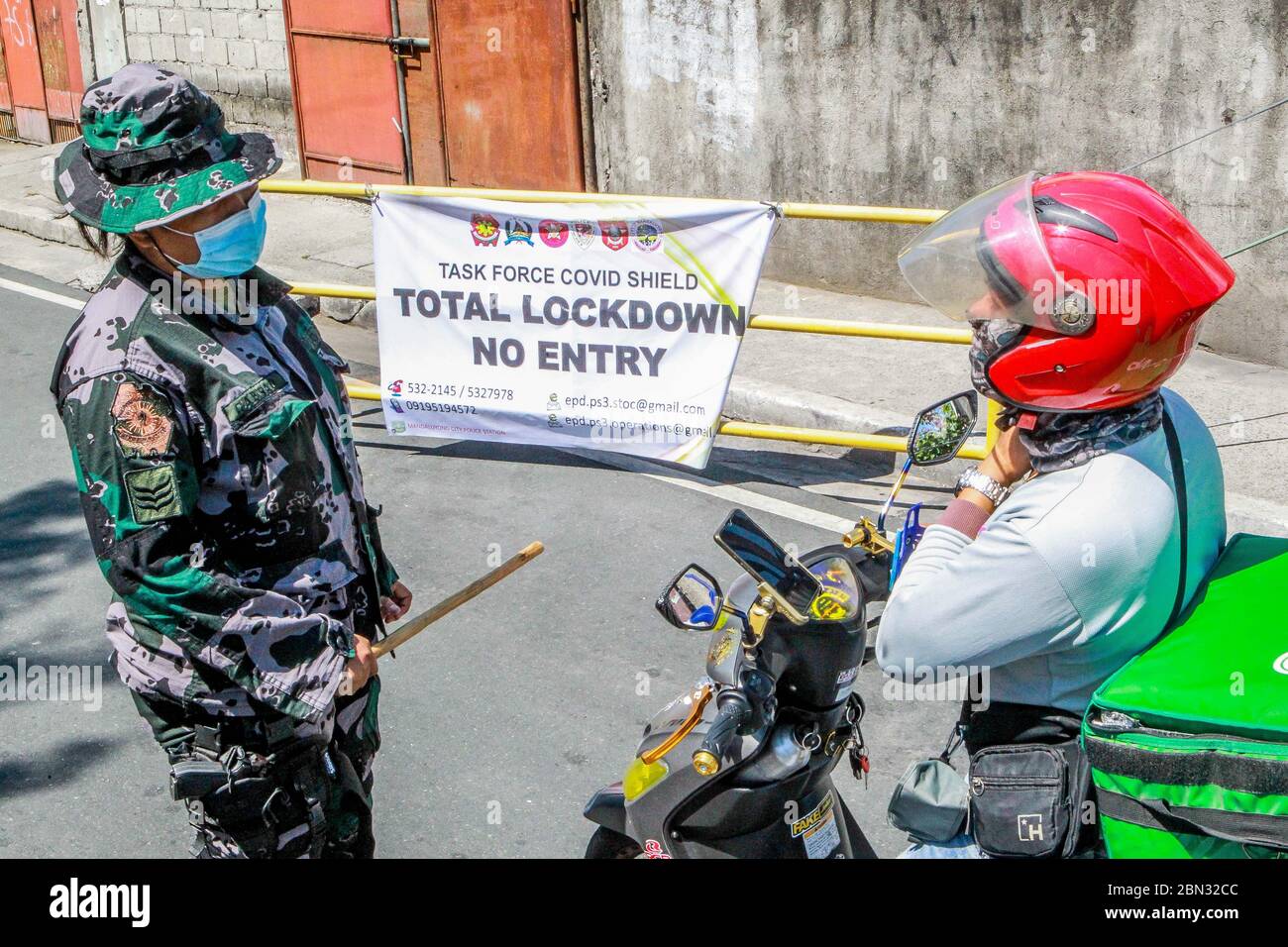 Mandaluyong City, Philippinen. Mai 2020. Ein Polizist inspiziert am 12. Mai 2020 einen Motorradfahrer in einem Dorf, das in Mandaluyong, Philippinen, gesperrt wurde. Die philippinische Regierung gab am Dienstag bekannt, dass Metro Manila, die Provinz Laguna auf der Hauptinsel Luzon und Cebu City in der Mitte der Philippinen von Mai 16 bis Mai 31 unter "verbesserte Quarantäne der Gemeinden" gestellt werden. Oder nach der Lockdown-Zeit in vielen Teilen des Landes im Mai 15 hinfällig. Quelle: Rouelle Umali/Xinhua/Alamy Live News Stockfoto