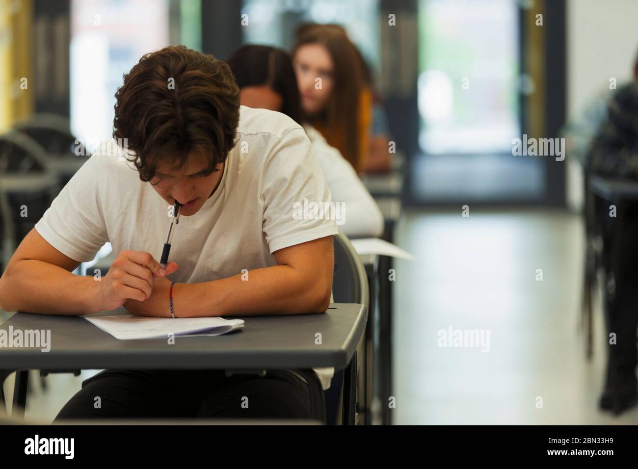 Fokussierte High School Jungen Schüler, die Prüfung am Schreibtisch im Klassenzimmer Stockfoto