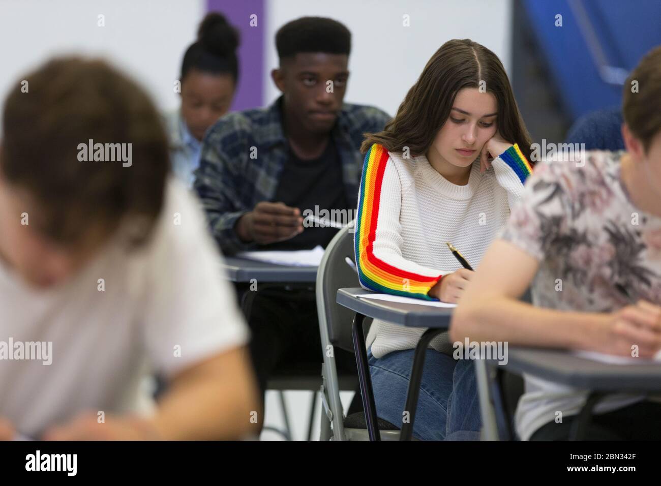 Schüler, die an den Schreibtischen im Klassenzimmer Prüfung ablegen Stockfoto