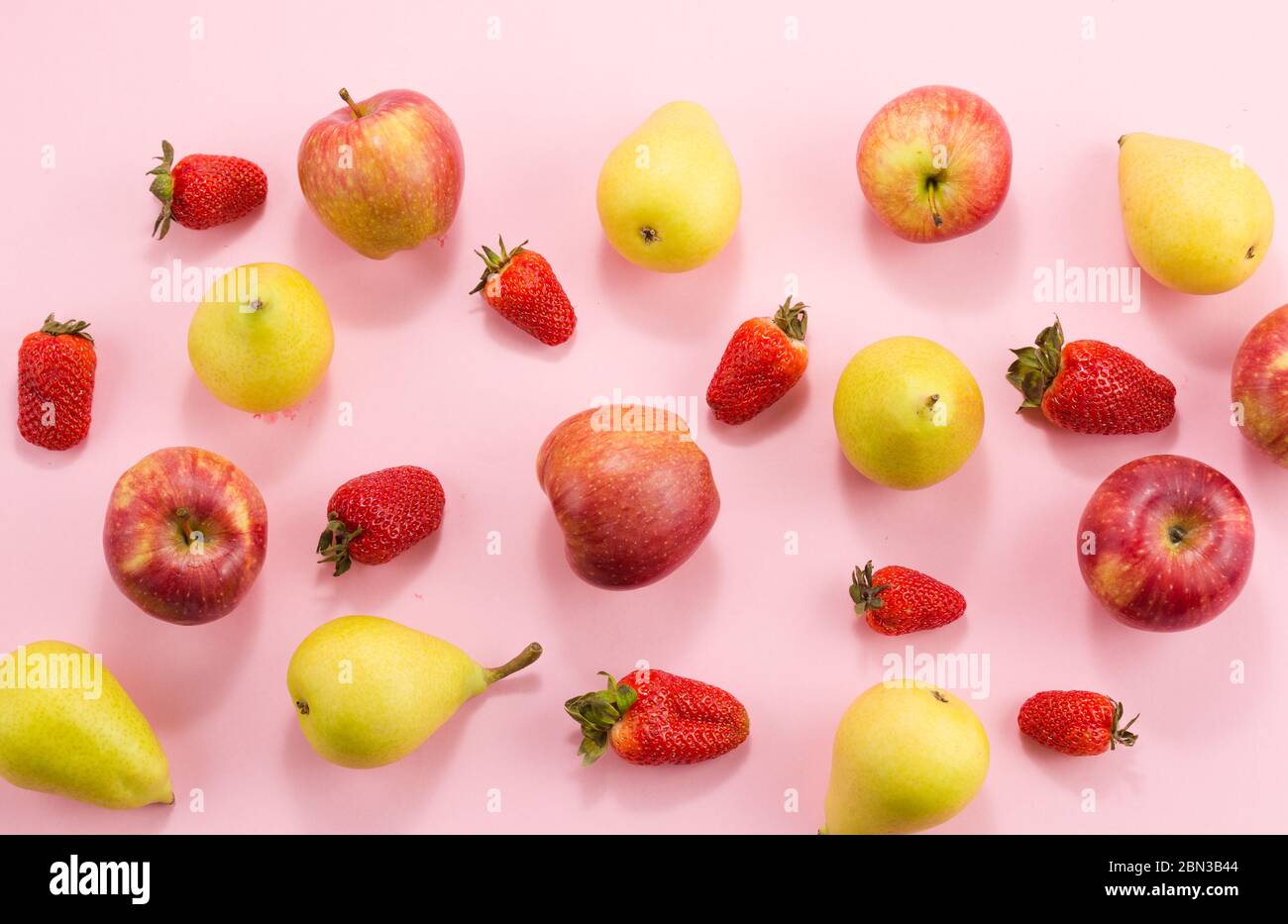 Erdbeerbirnen und Äpfel auf rosa Hintergrund. Stockfoto