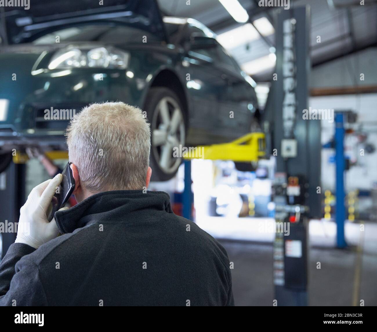 Männliche Mechaniker sprechen auf Smartphone in Auto-Werkstatt Stockfoto