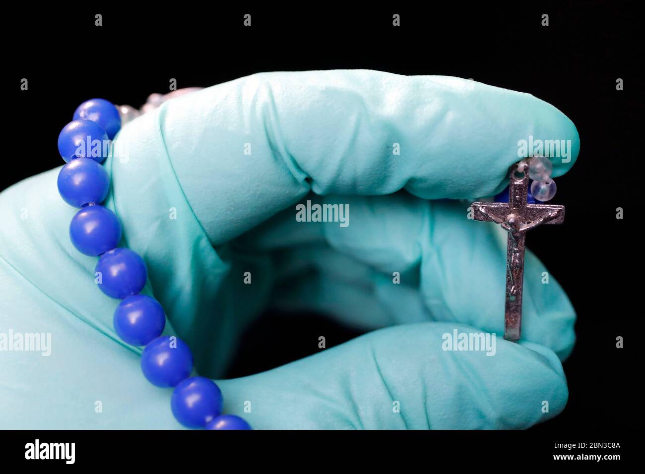 Coronavirus Epidemien ( covid-19 ). katholische beten den Rosenkranz mit einem Schutzhandschuh. Stockfoto