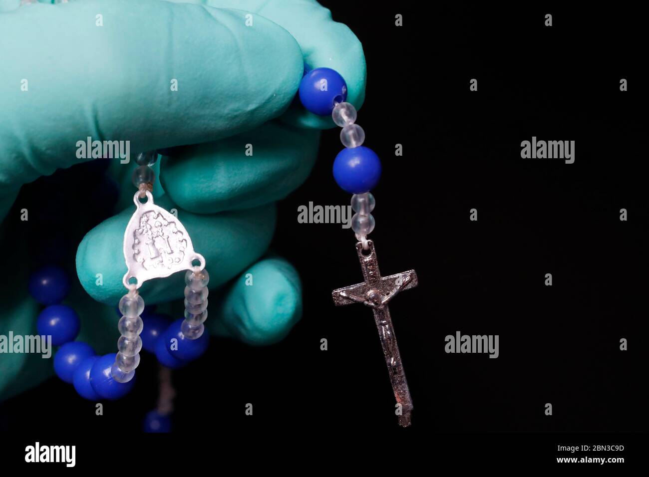 Coronavirus Epidemien ( covid-19 ). katholische beten den Rosenkranz mit einem Schutzhandschuh. Stockfoto