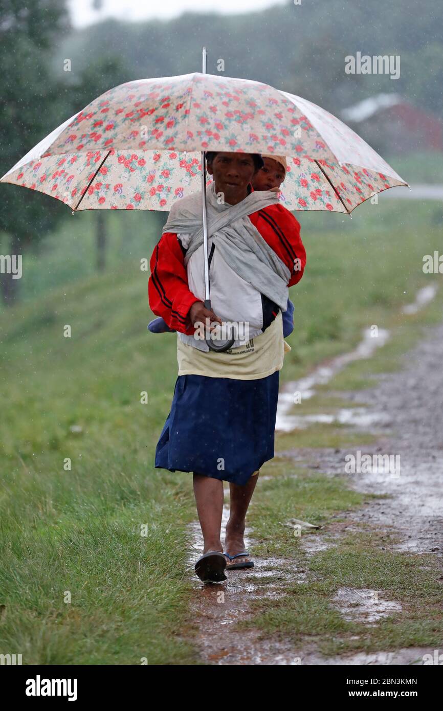 Frau mit Sonnenschirm geht im Regen. Madagaskar. Stockfoto