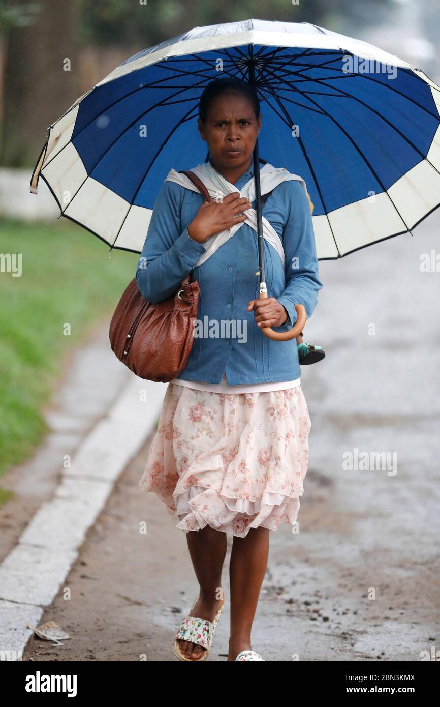 Frau mit Sonnenschirm geht im Regen. Antsirabe. Madagaskar. Stockfoto