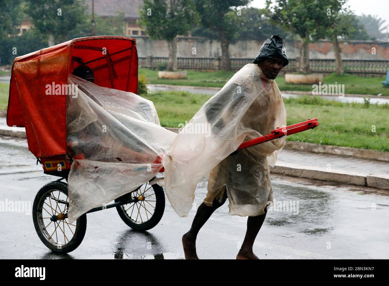 Pousse-Pousse (Rikscha) Fahrer bei starkem Regen. Antsirabe. Madagaskar. Stockfoto