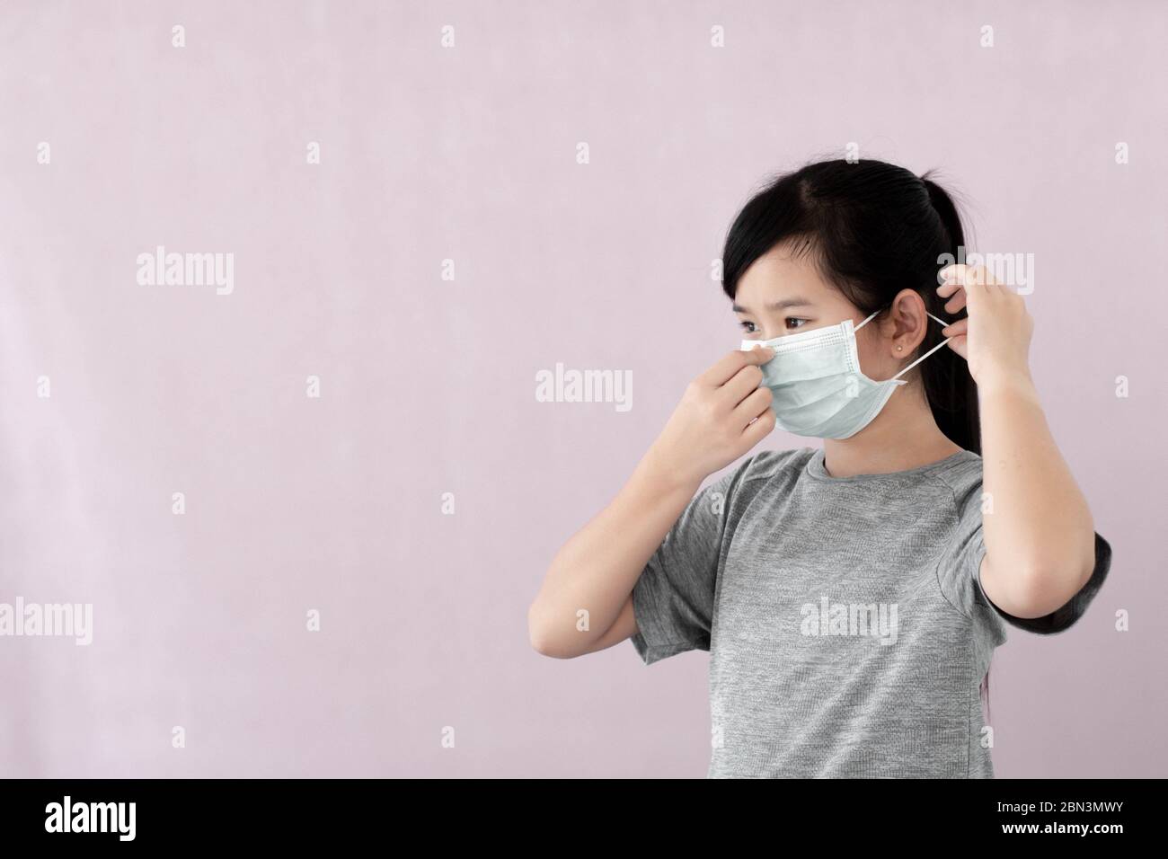Kleines Mädchen mit steriler Maske auf grauem Hintergrund isoliert Coronavirus & PM 2.5 Luftverschmutzung zu verhindern, zeigen asiatische Mädchen, wie man Virus prot tragen Stockfoto