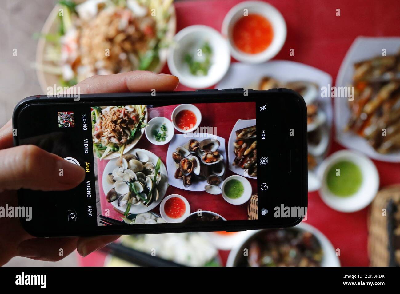 Street Sea Food Restaurant. Eine Frau nimmt das Essen per Handy in die Hände. Quy Nhon. Vietnam. Stockfoto