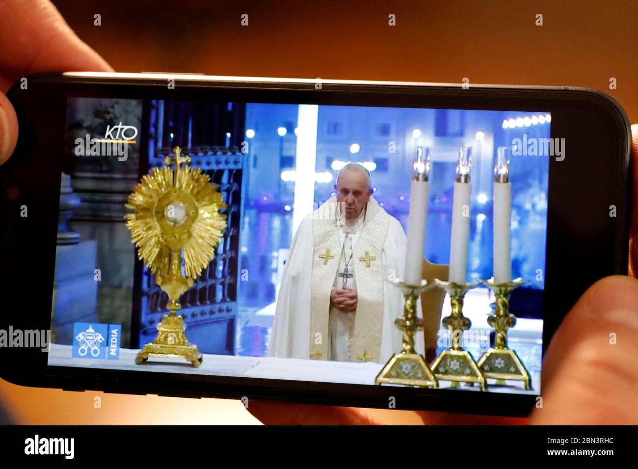 Coronavirus (COVID-19)-Epidemie. Eindämmungsmaßnahmen. Christain beobachtet auf dem Smartphone die Feier der katholischen Messe mit Papst Franziskus. Youtube. Stockfoto