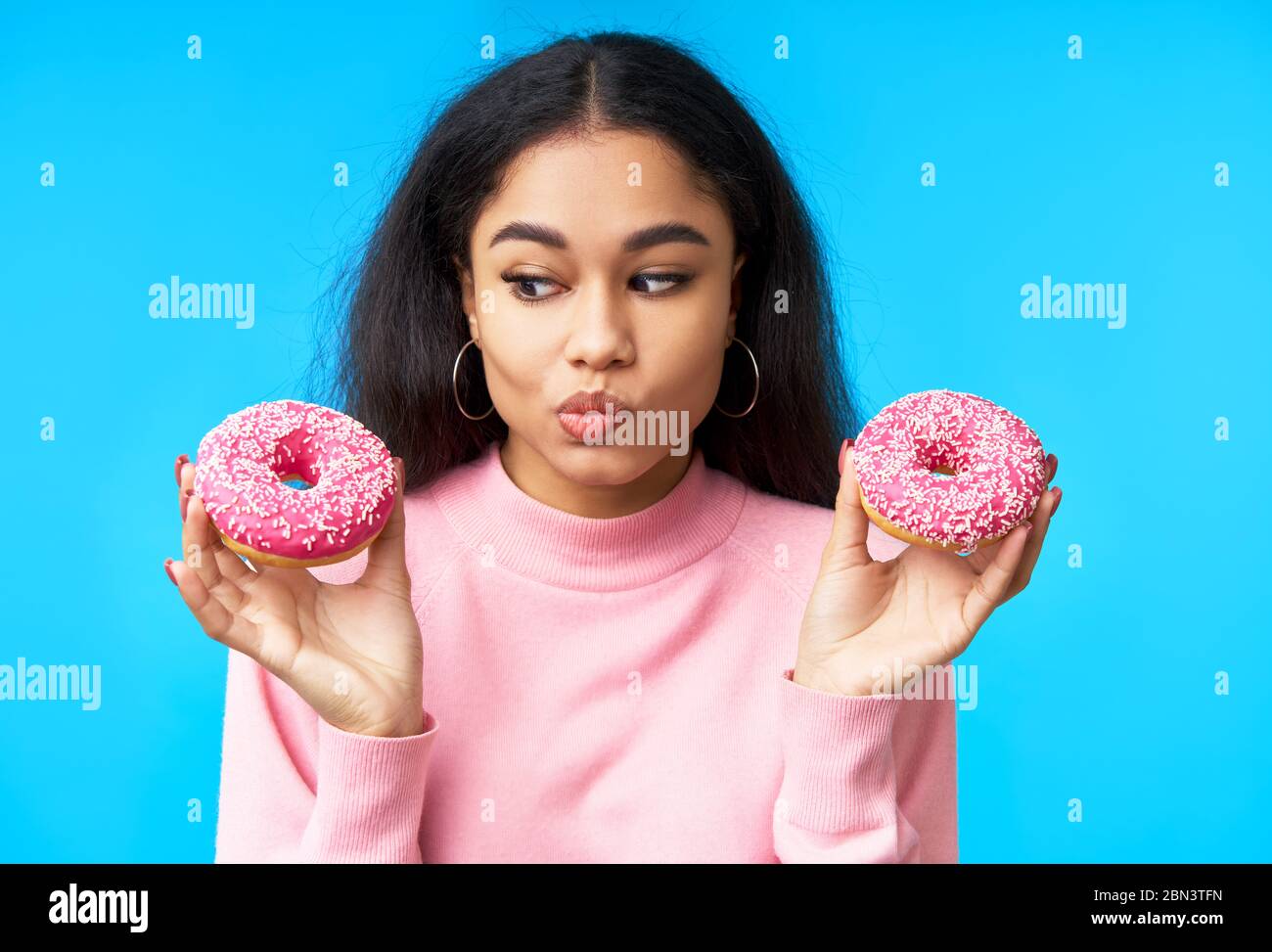 Nachdenkliche hungrige Frau Wahl zwischen Donuts. Versuchungsessen. Diät-Konzept Stockfoto