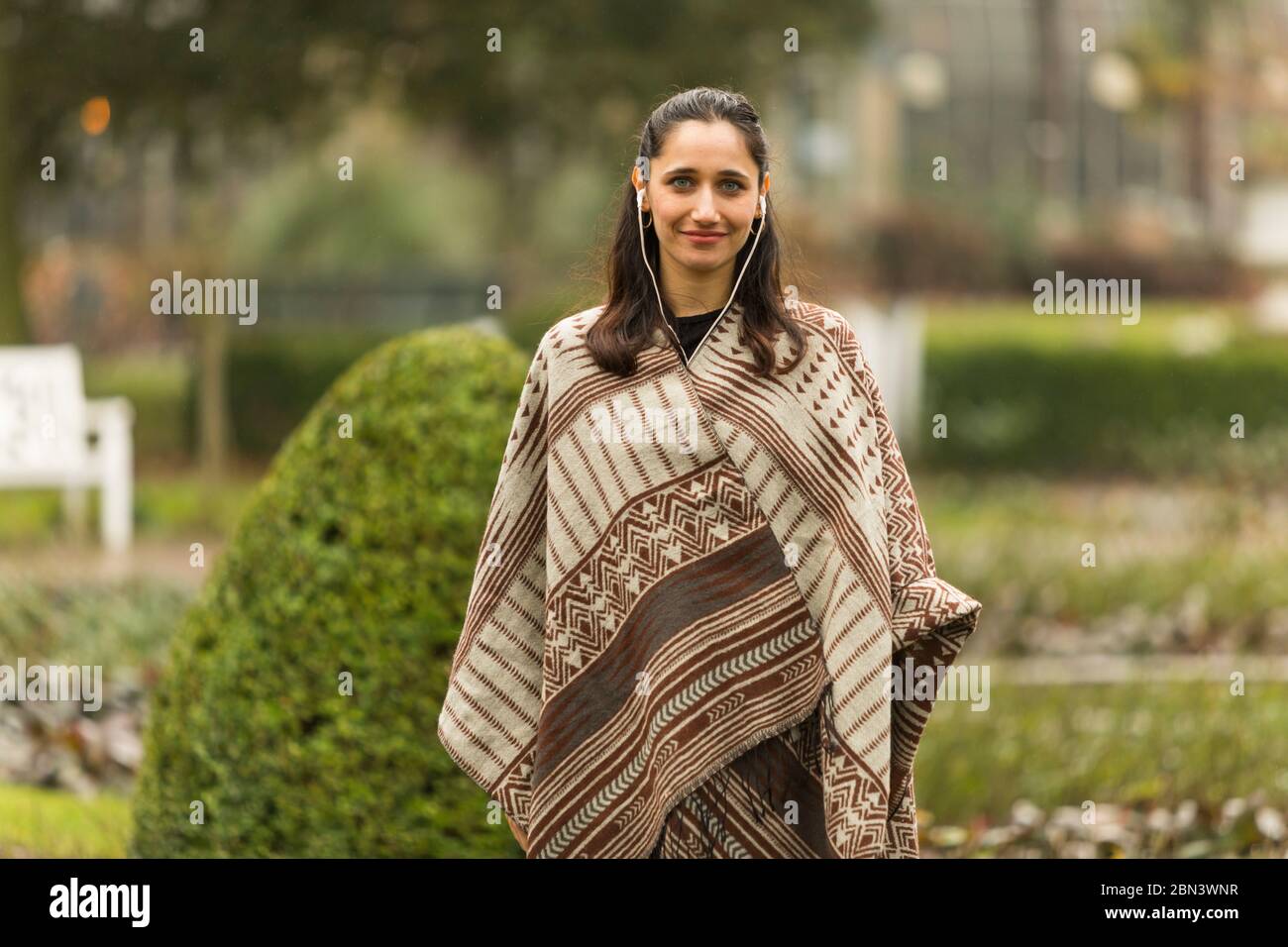 Real Life weibliche Modell trägt Poncho posiert im Garten. Stockfoto