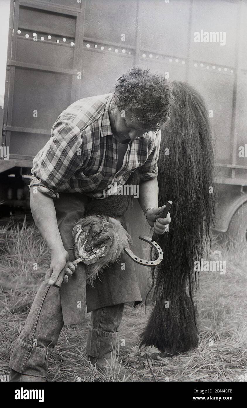 1987, draußen auf der Gypsy Horse Fair, ein Farrier, der ein Karre-Pferd umhackt, Yorkshire, England, Großbritannien. Stockfoto